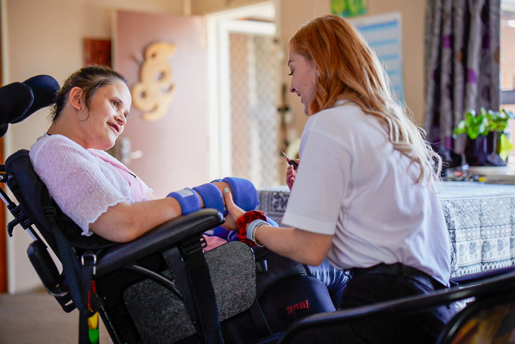 A carer helps a woman in a wheelchair.