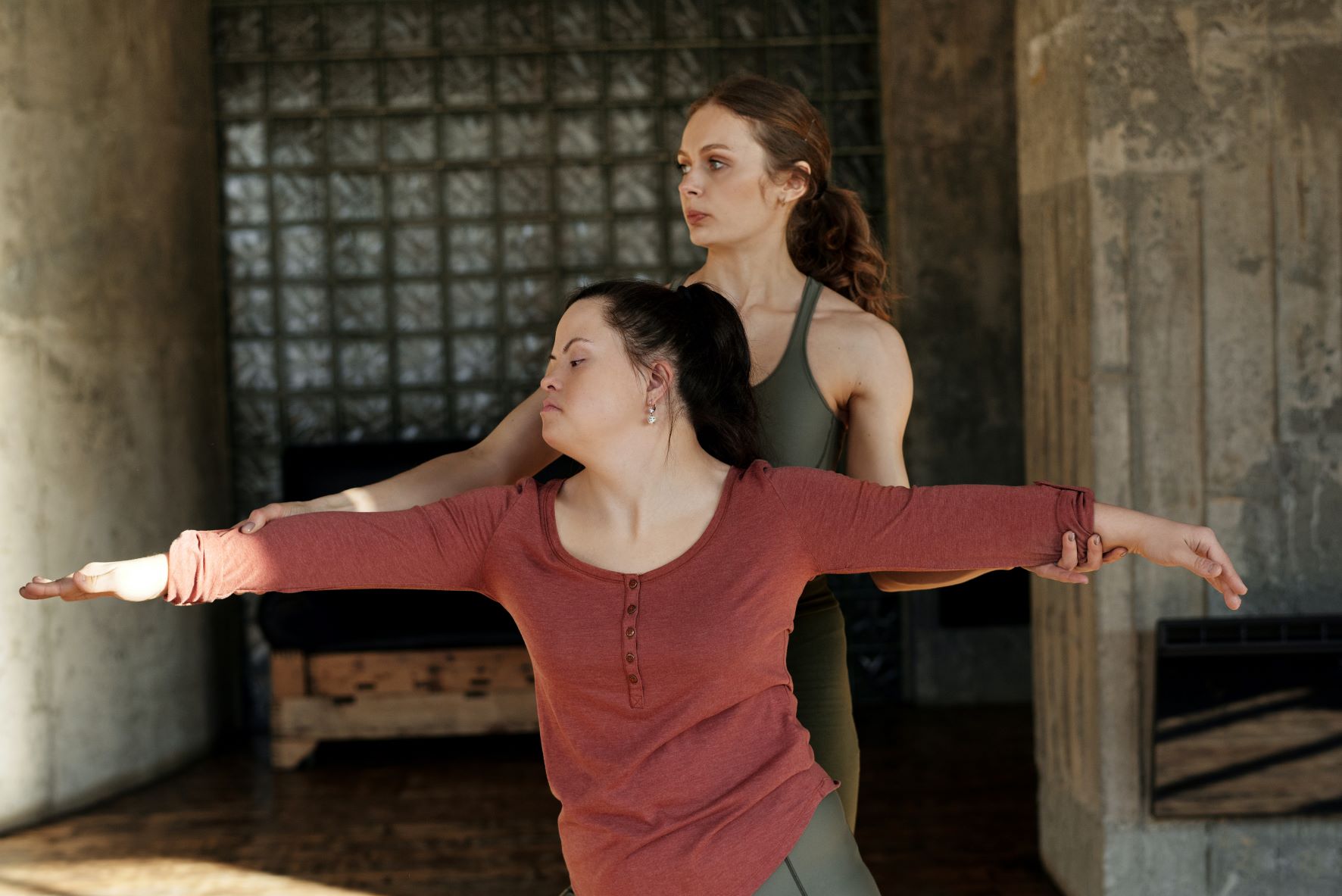 A dance instructor teaches a woman with Down Syndrome.