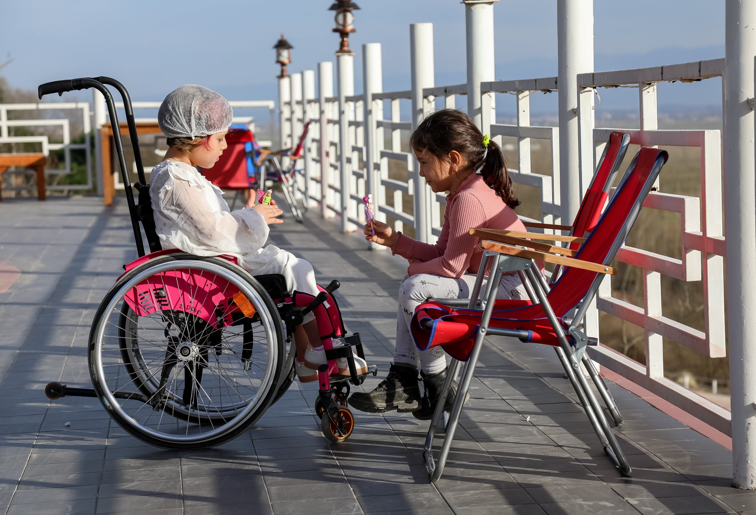 2 girls, one in a wheelchair, play with dolls.