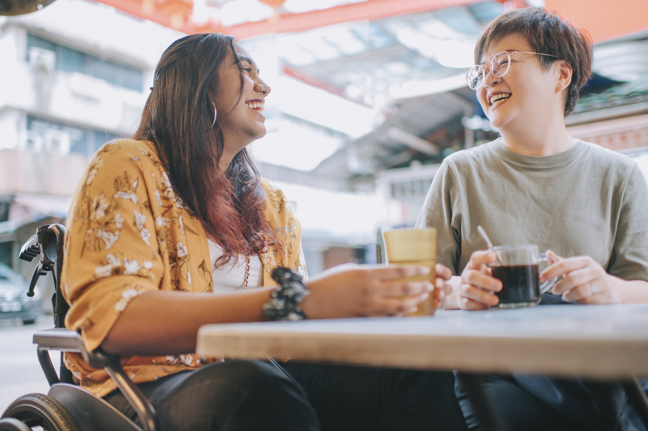 asian indian woman with disability in wheelchair enjoying street food in petaling street with her chinese female friend